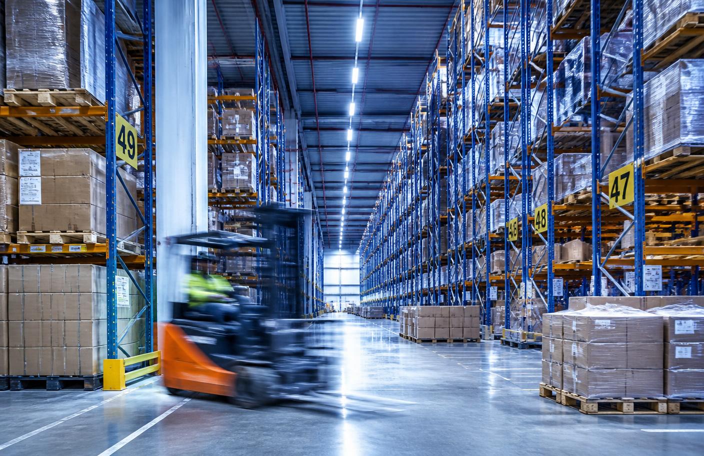 Interior de um centro de distribuição com racks e operação em movimento